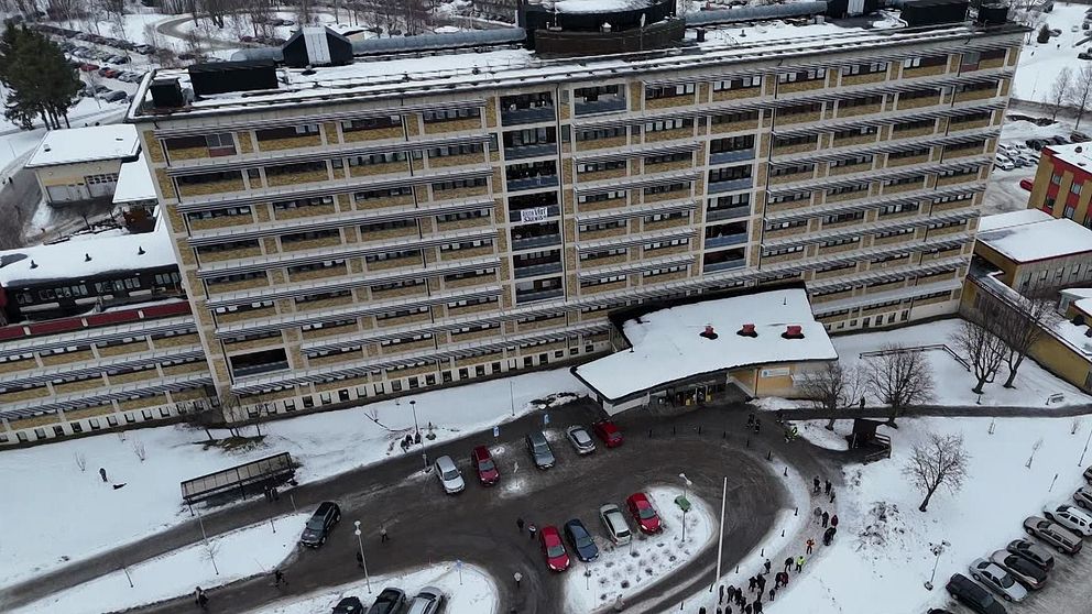 Flygbild av ett stort, snötäckt bostadskomplex med bilar parkerade framför.