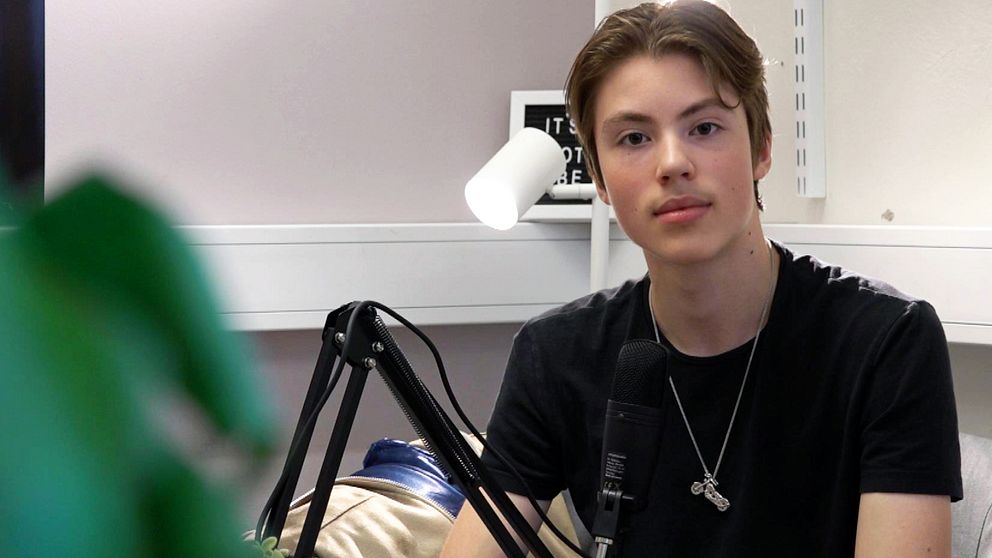 en kille sitter med svart t-shirt vid en mikrofon