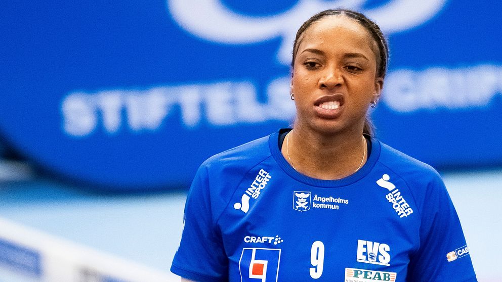 Volleybollspelare i blå tröja nummer 9 vid nätet, inomhussporthall.