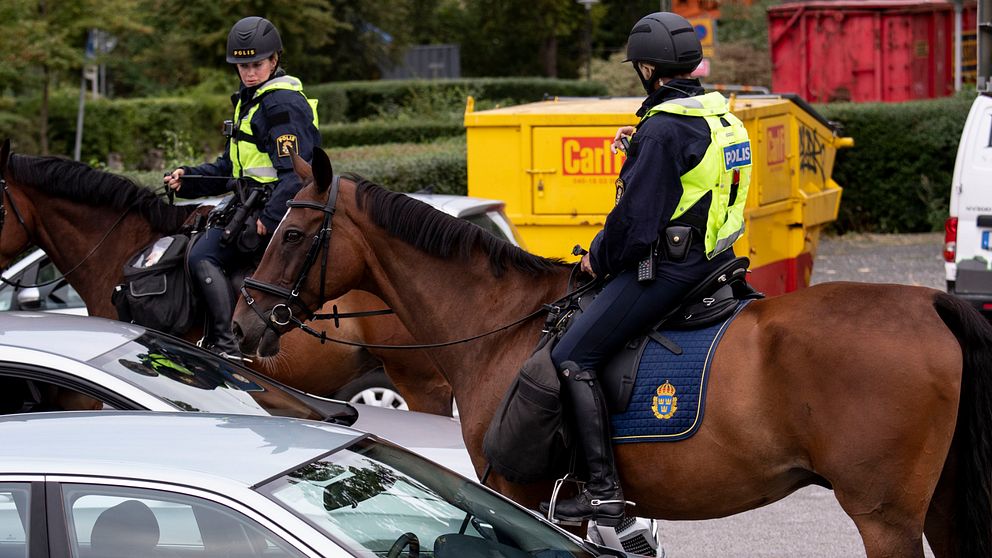 Två ridande poliser på bruna hästar.