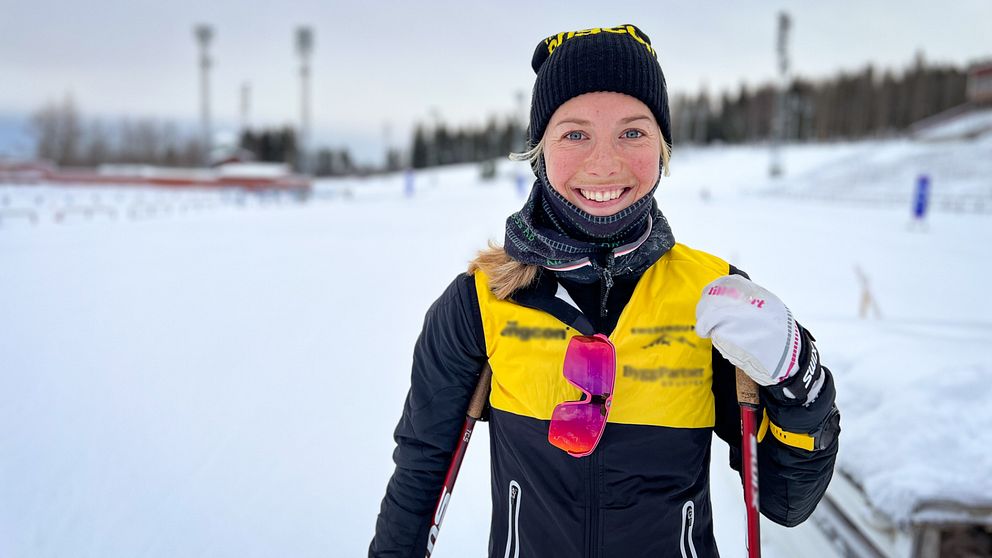 Ung kvinna i skidkläder ler mot kameran på Östersunds skidstadion