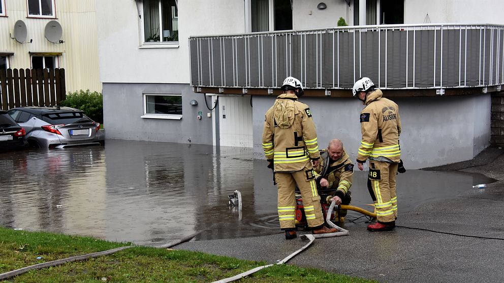 Brandmän pumpar vatten på översvämmad parkering.