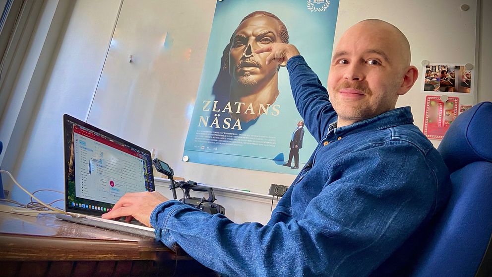 Filmare Olle Toftenow pekar på filmposter bredvid en dator i ett kontor.