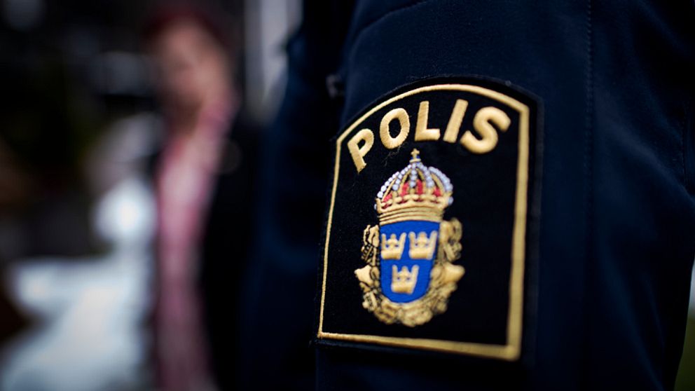 Närbild på en polisuniform med emblem.