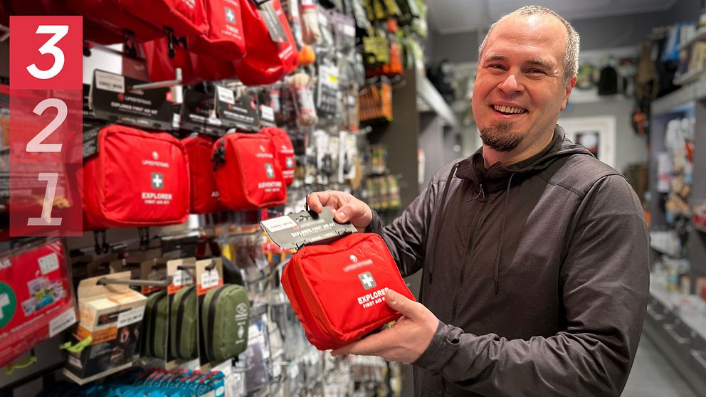 En glad man håller i en röd första hjälpen-väska.