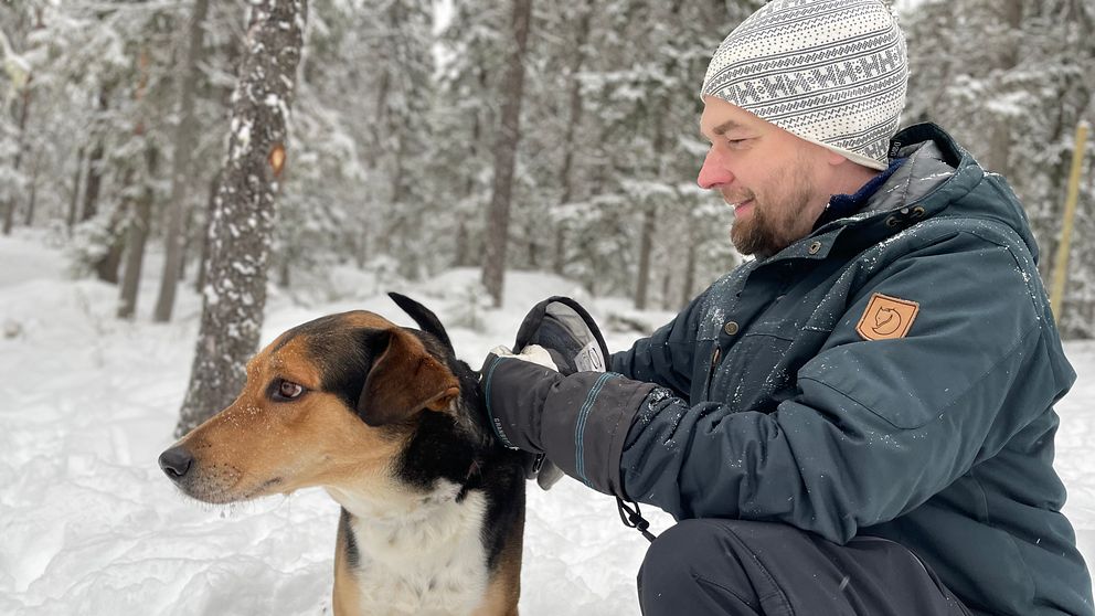 Hundägaren Christer Nilsson sitter med sin hund i snön i hundparken i Junsele