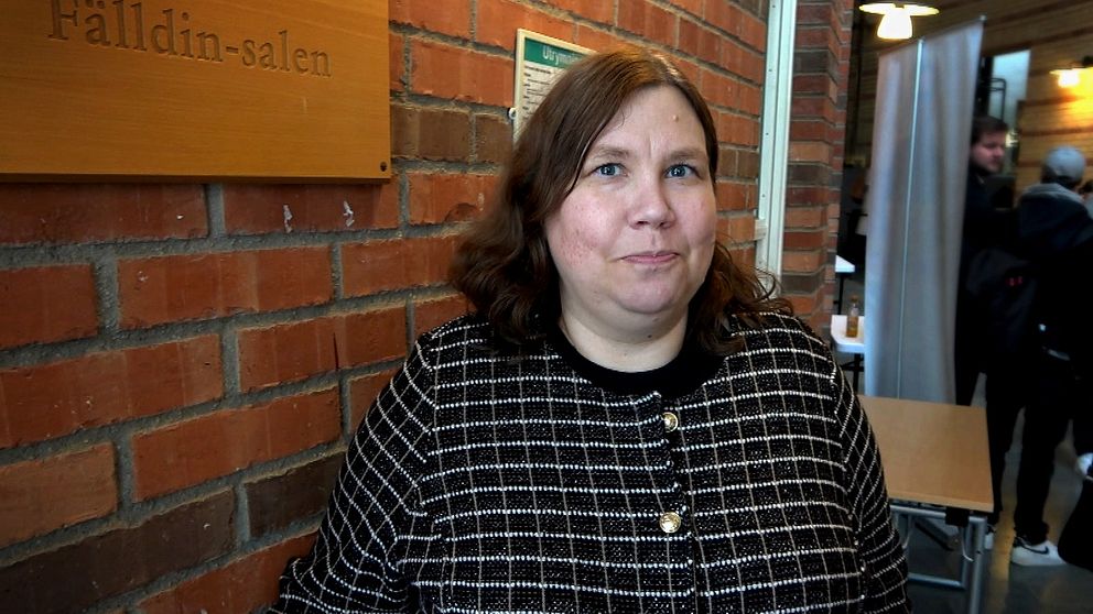 Sofie Blombäck, statsvetare står framför en vägg i brunt tegel i en av Mittuniversitetets lokaler i Sundsvall.