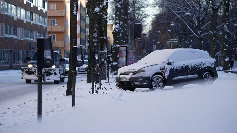 En ensam och igensnöad elbil på en parkering.