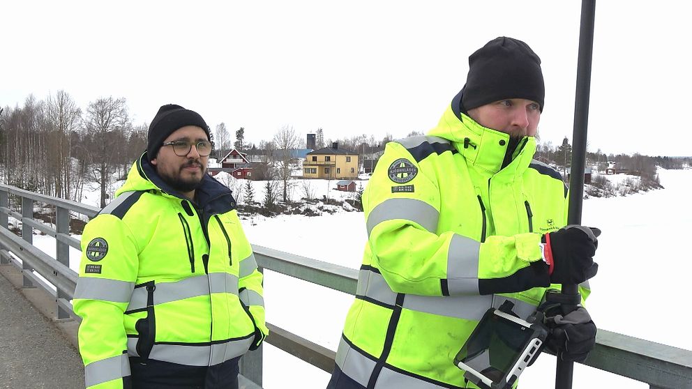 Två män i varselkläder monterar vattenmätare i Övertorneå för att kunna följa vattenflödet inför vårfloden.