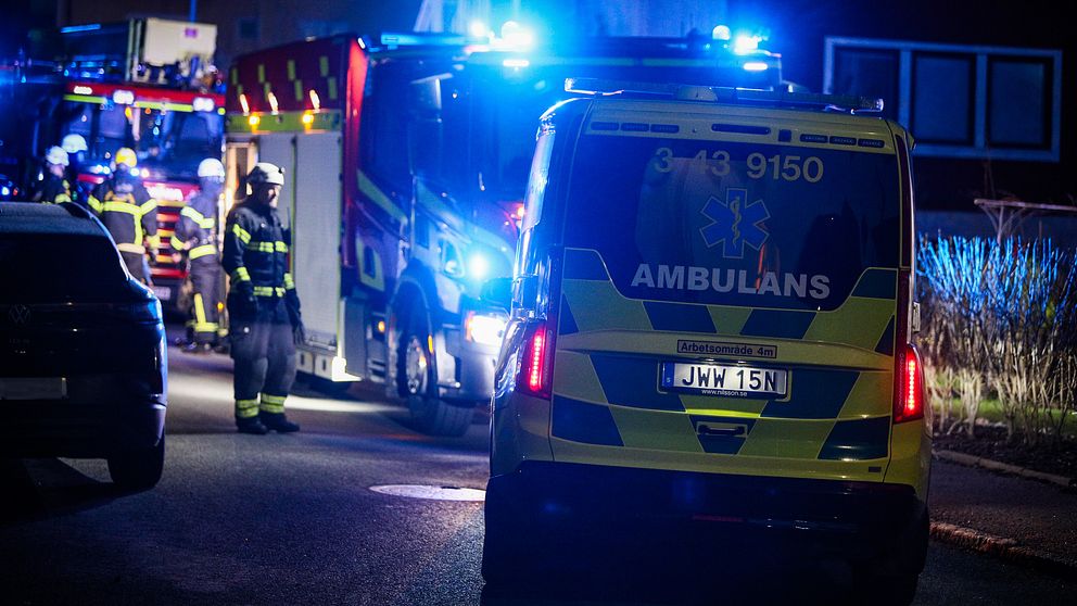 Räddningspersonal och ambulanser på plats vid en utryckning på en mörk väg.
