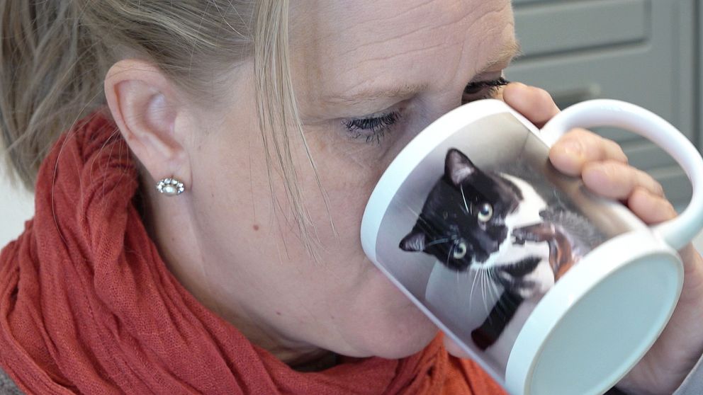 Kvinna dricker från kaffekopp som har en bild på en katt