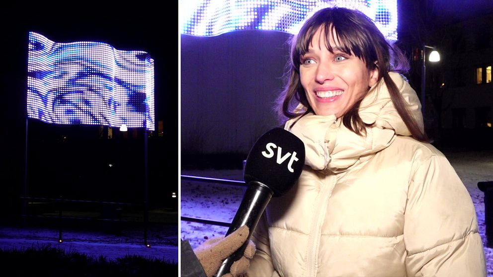 konstnären Izabel Lind från Stockholm har skapat Stream, som syns till vänster i bild, det är en stor skylt med lampor som lyser i blått och vitt. Till Höger står konstnären iklädd vinterjacka.