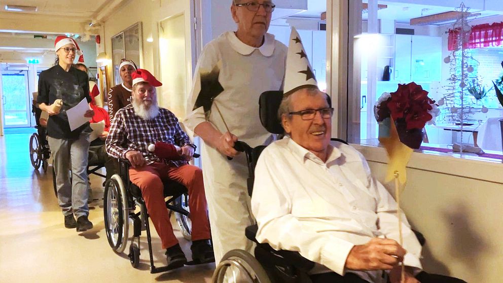 Luciatåg med äldre på äldreboende. Stjärngosse i rullstol, tomte i rullstol.