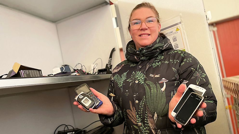 kvinna som håller i gamla mobiltelefoner