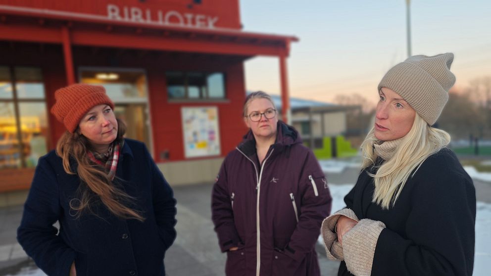 Tre personer står utanför ett bibliotek i vinterkläder.