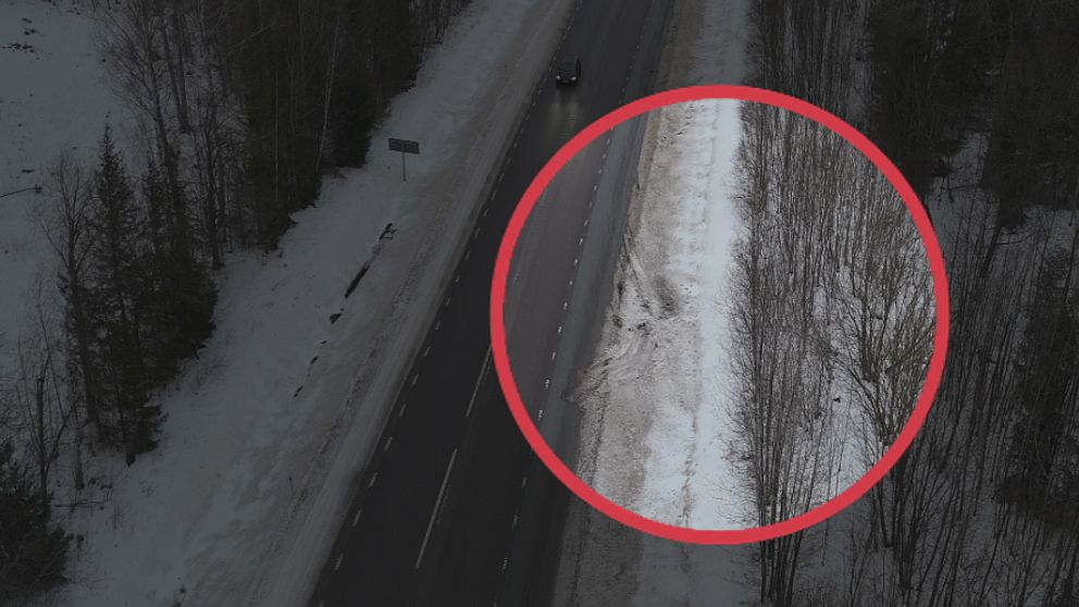 En väg med snö på kanterna, där ett cirkelformat område markerar en del av den snötäckta vägkanten med några träd i bakgrunden.