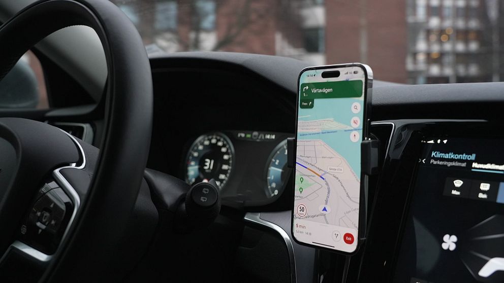 En mobil med kartapp placerad på instrumentbrädan i en bil.