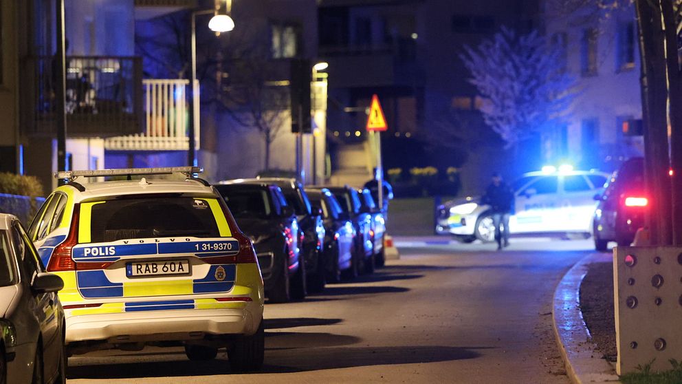 Polisbilar på plats längs en gata i ett bostadsområde i Södra Hammarbyhamnen efter fredagkvällens skottlossning.