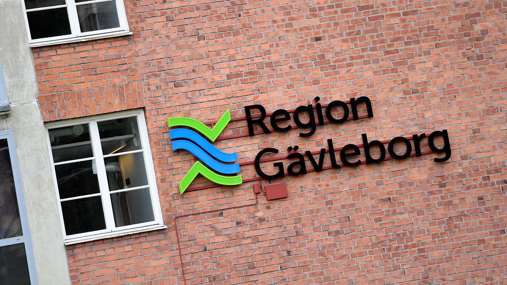 Region Gävleborgs logga på en röd tegelvägg vid ett fönster.