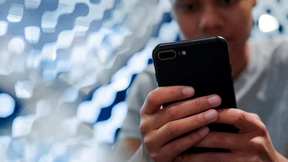 Ungdom sitter med en mobiltelefon.