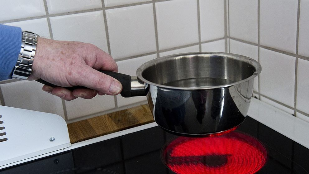 kastrull fylld med vatten. kastrullen hålls strax ovanför en röd upphettad spisplatta.