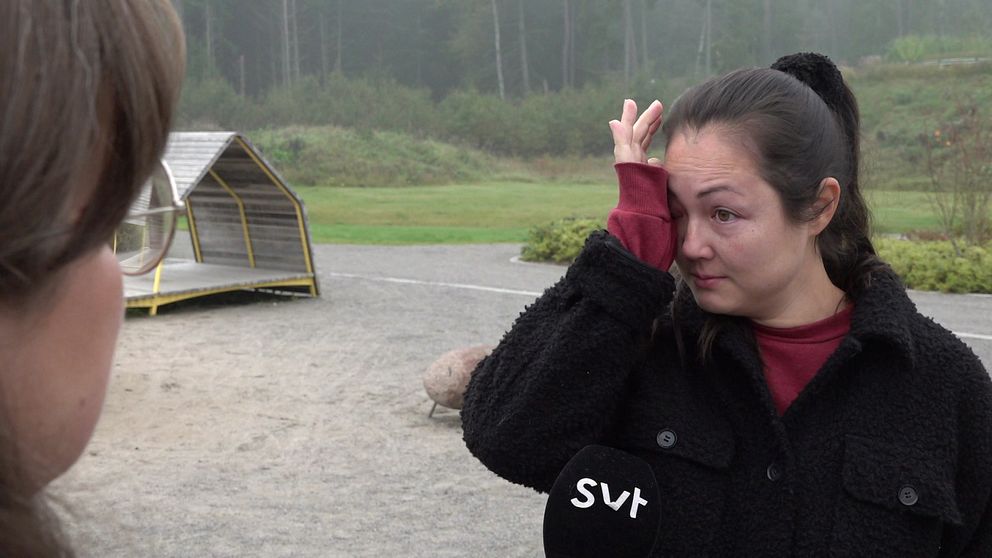 En kvinna torkar en tår. Hon står i en lekpark i Fullerö.