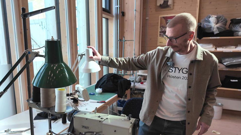 David Åkerlund visar en syateljé med symaskin och arbetsbord i bakgrund.