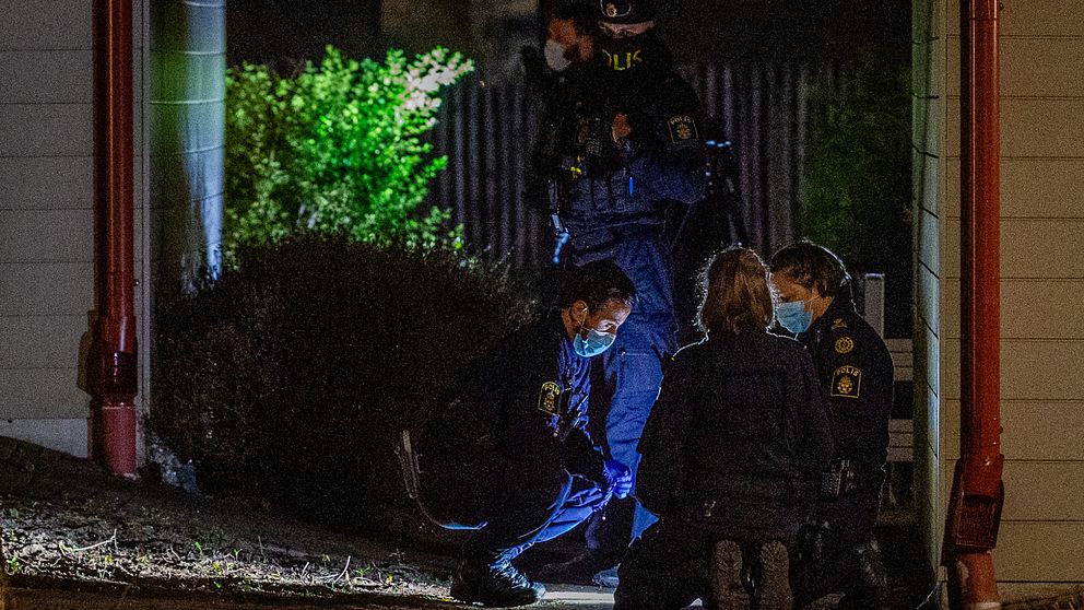 Flera poliser undersöker brottsplatsen i Klippan med ficklampor nattetid.