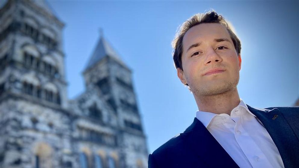 Lundastudenten Elliot Berggren från Kreditkassan framför domkyrkan i soligt väder.