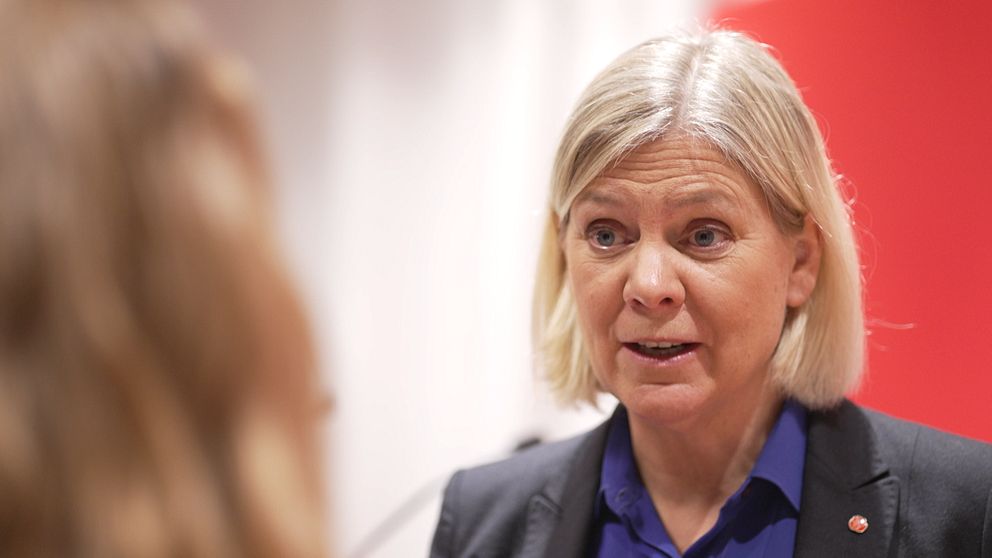 Blond kvinna med når ner till nacken iklädd mörk kavaj med Socialdemokraterna-pin och lila skjorta