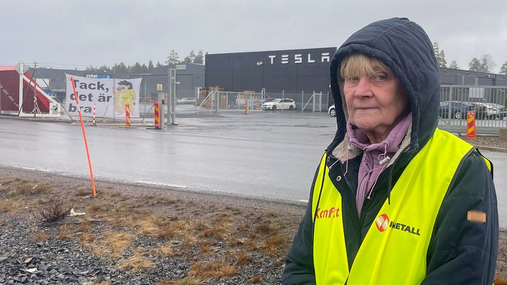En kvinna som står vid en Tesla anläggning i Jönköping