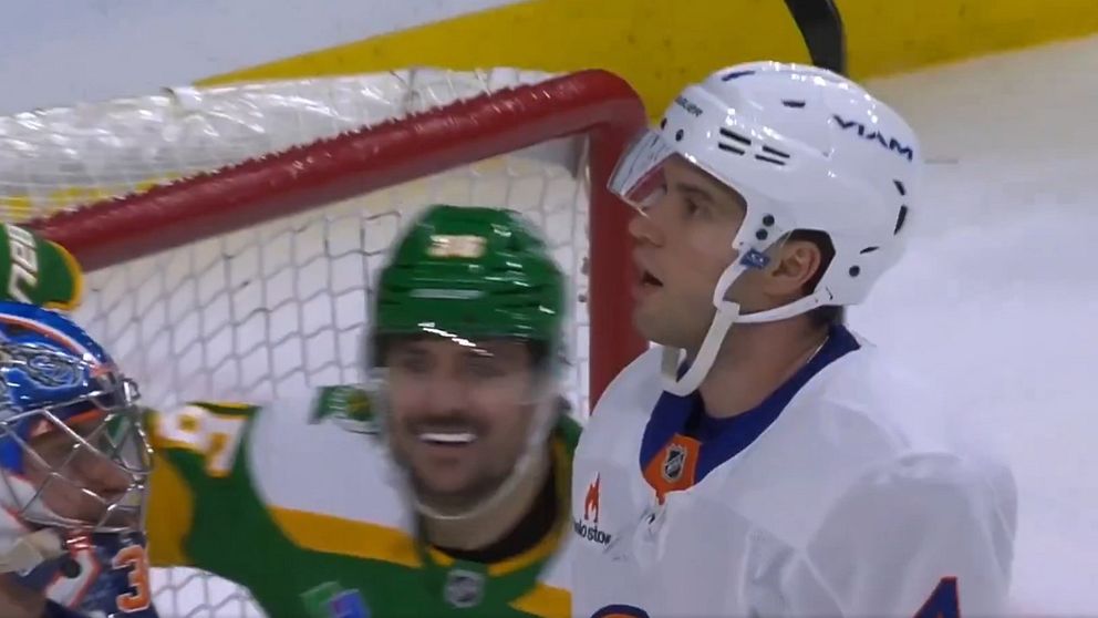 New York Islanders back Tony Deangelo ser förbluffad ut i sin vita ishockeyhjälm. Bakom honom firar Mats Zuccarello i sin gröna hjälm.