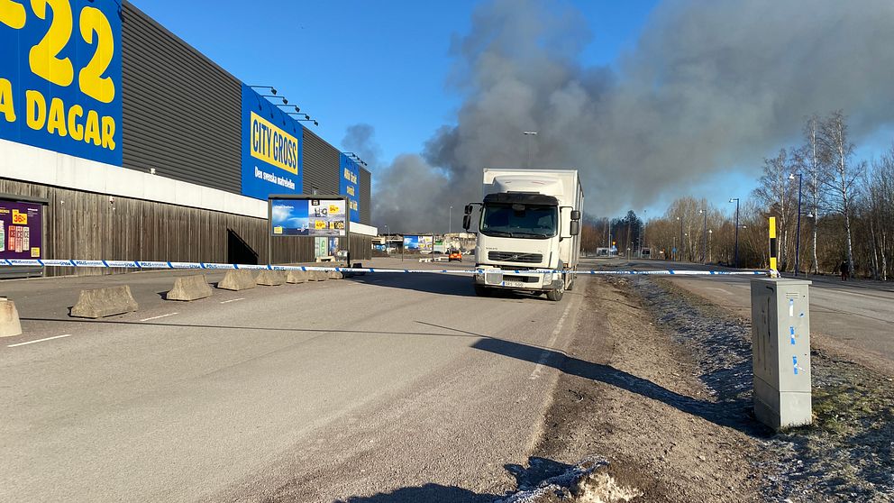 Stora delar av parkeringen till matbutiken intill branden är under torsdagen avspärrad på grund av röken.
