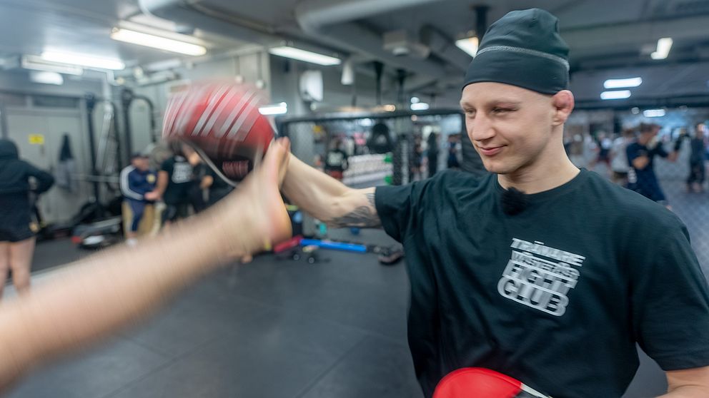 Person sparkar mot en handske på kampsportträning.