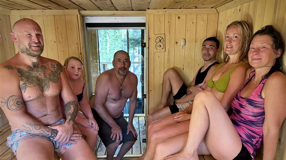 Flera bastubadare sitter i en träbastu på Bölesholmarna i Umeå under värmeböljan.