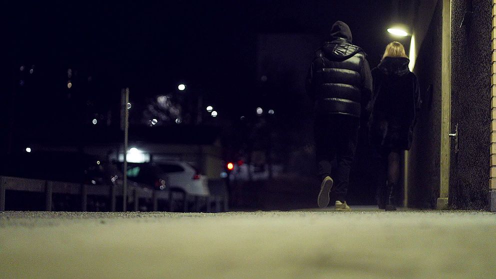 Två personer gåendes på gata i mörker.