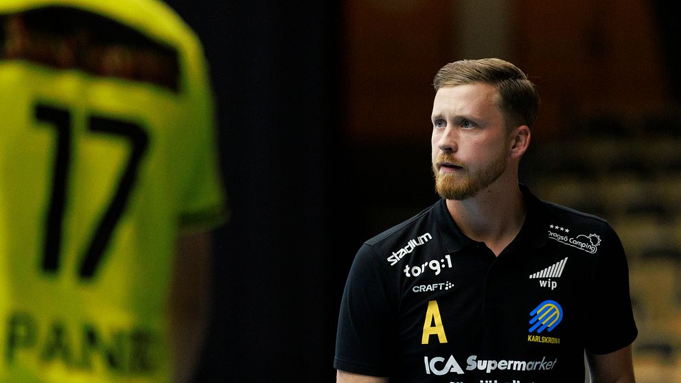 Handbollsspelare i svart tröja och nummer 17 i gul tröja på spelplanen.