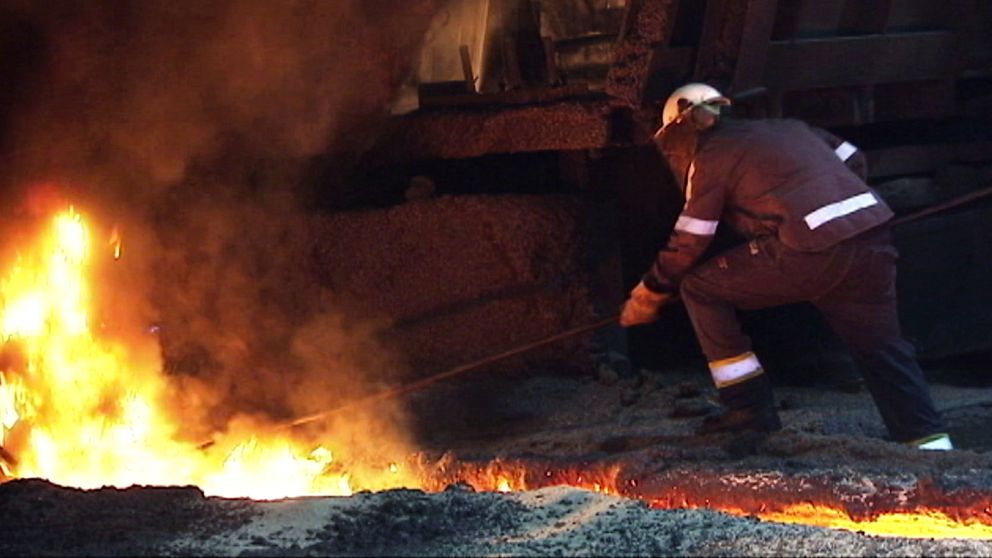 En arbetare står och jobbar i ett stålverk där elden sprakar.sugn.