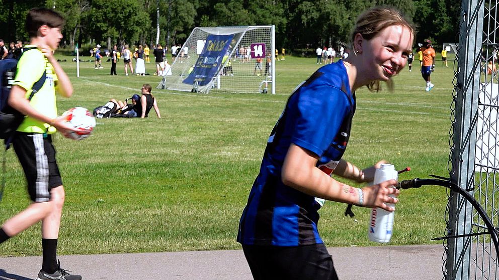 Tjej i fotbollskläder som fyller sin vattenflaska.
