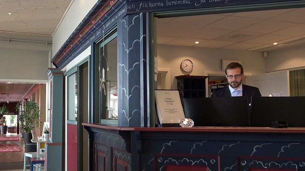 Man som står i receptionen och skriver på dator