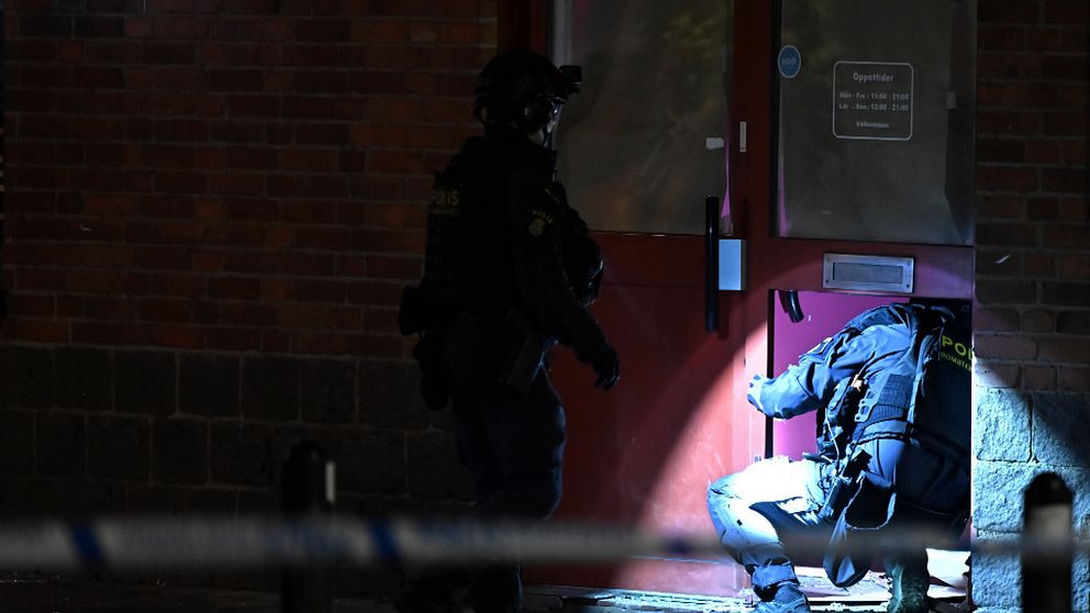 Två poliser undersöker en port i mörker efter explosion i Gamlestaden, Göteborg.