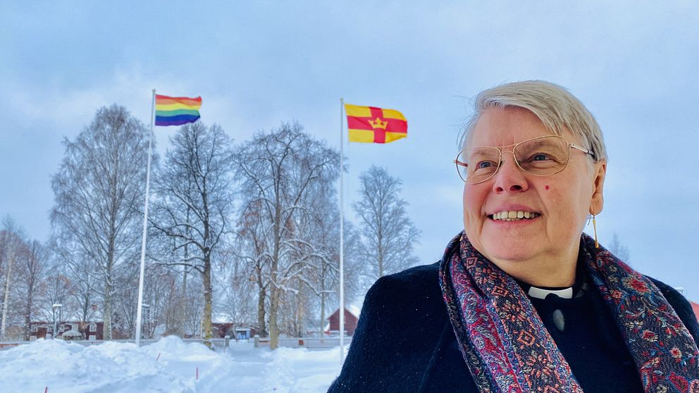 Präst i Gagnef och tittar mot himlen, med Svenska kyrkans flagga i bakgrunden.