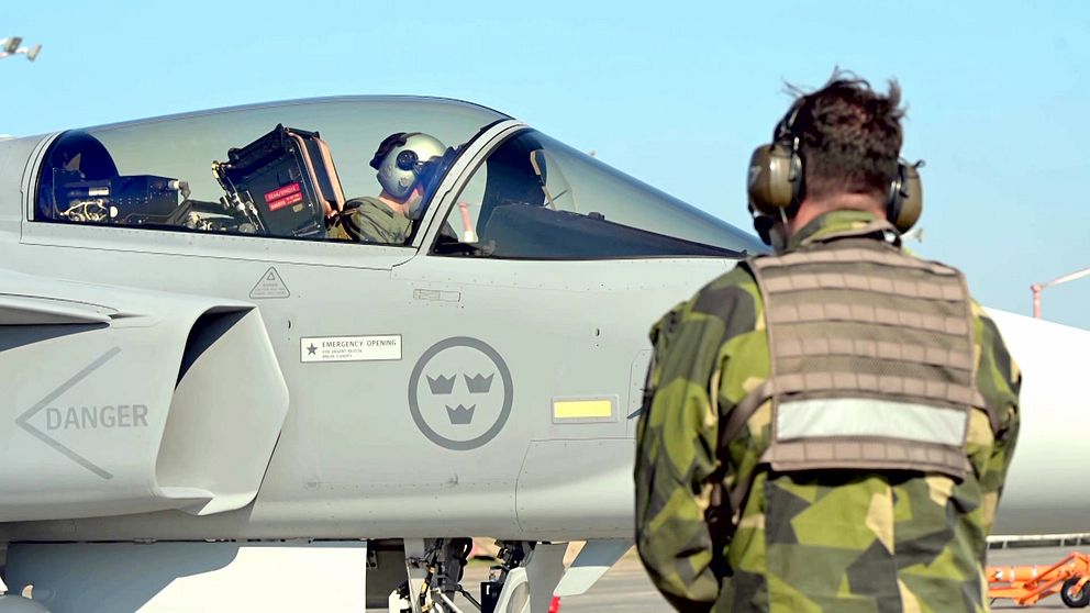 Pilot i JAS 39 Gripen kommunicerar med markpersonal i uniform.