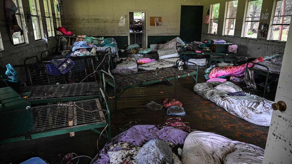 Översvämmat sovrum med blöta madrasser och sängar i oordning efter katastrof.