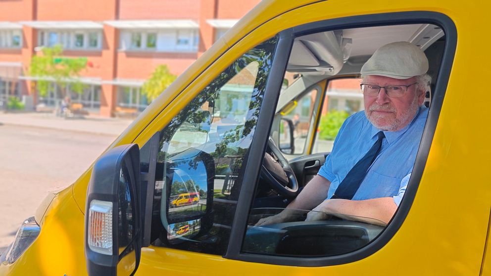 En man sitter i en gul buss på förarsätet och tittar ut genom fönstret