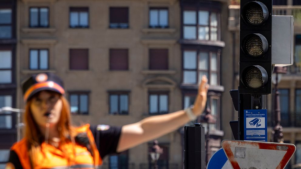 Trafikpolis dirigerar trafiken vid ett rött trafikljus i stadsmiljö.