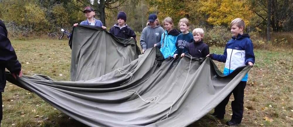 Elever från Mullhyttansskola, åk 5, hjälps åt att vika ihop ett militärtält.