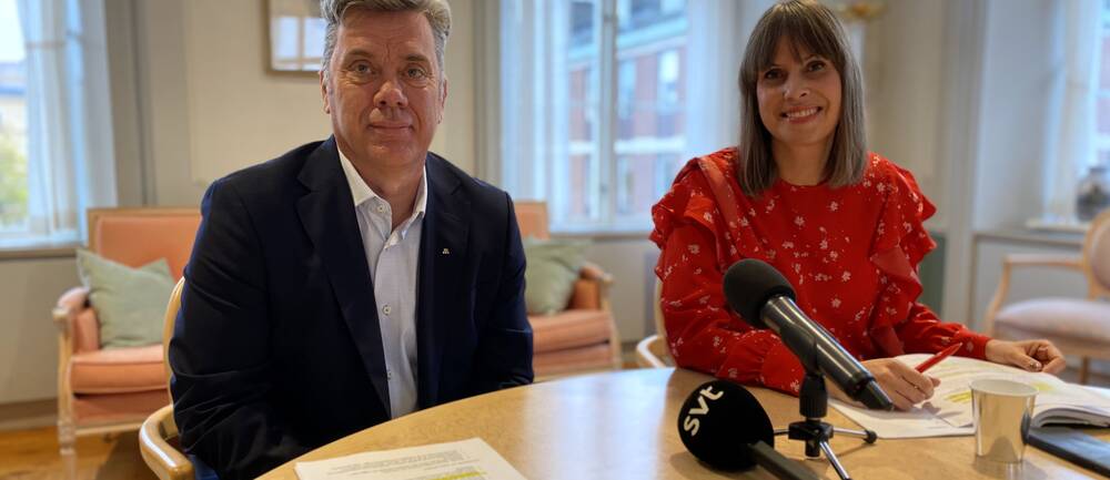 en man och en kvinna – politiker som sitter i ett rum med mikrofoner framför sig