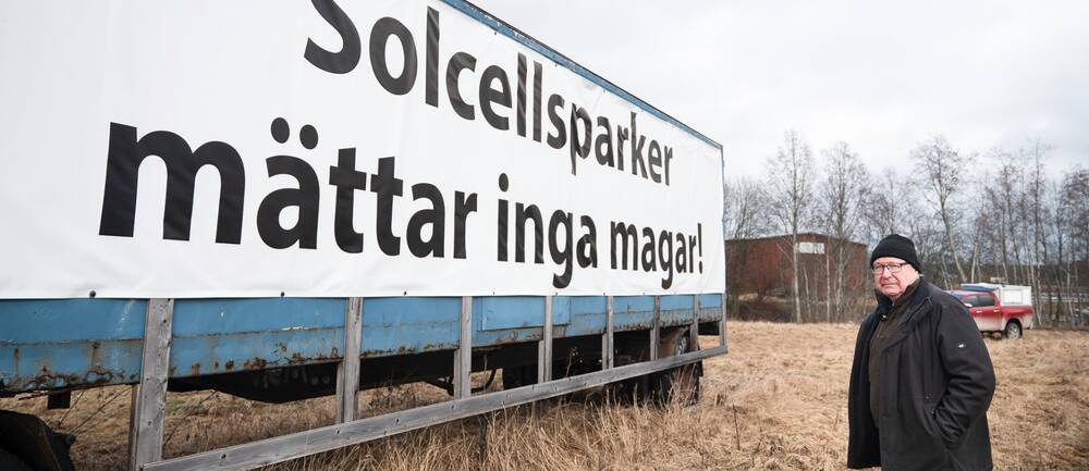 Lars-Gunnar Sandin står på åkermark vid sin stora uppsatta skylt där det står ”Solcellsparker mättar inga magar”. Nu ska skylten ner.