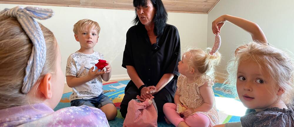 Dagmamman Eva-Karin Andersson i Lomma sitter på mattan i ring med barnen.